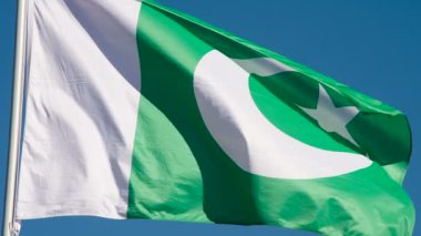 Pakistan Bayrağı Rüzgarı Kıpırdatıyor. Büyük Eyalet Bayrağı güneş tarafından aydınlatılır ve mavi gökyüzüne karşı destansı bir şekilde dalgalanır. Slow Motion 240 fps