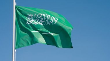 Suudi Arabistan Bayrağı Rüzgarı Kıpırdatıyor. Büyük Eyalet Bayrağı güneş tarafından aydınlatılır ve mavi gökyüzüne karşı destansı bir şekilde dalgalanır. Slow Motion 240 fps