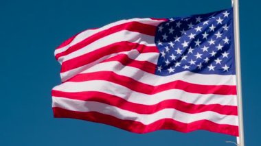 Banner USA Waves the Wind. Büyük Eyalet Bayrağı güneş tarafından aydınlatılır ve mavi gökyüzüne karşı destansı bir şekilde dalgalanır. Slow Motion 240 fps