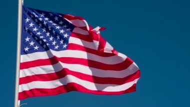 Banner USA Rüzgarı Kıpırdatıyor. Büyük Eyalet Bayrağı güneş tarafından aydınlatılır ve mavi gökyüzüne karşı destansı bir şekilde dalgalanır. Slow Motion 240 fps