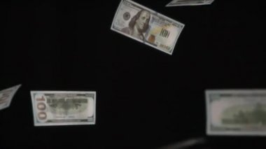 Para Yağmuru. Döngü. Parasal değerler 100 dolar ve yavaşça siyah arkaplan üzerine düşüyor. 240 fps hızla çekiliyor.