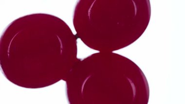 Üç Viburum Berry 'yi eziyorum. Viburnum böğürtlenleri sıkıştırılır ve parlak beyaz bir arka planda ezilerek sulu bir hamur ve parlak bir kabuk oluşturur. 120fps 'te atış