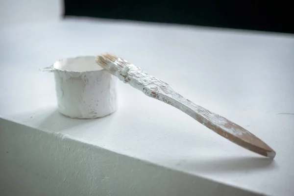 brush in white paint. working brush in white paint lies on a can of paint. white paint with a brush on a white background