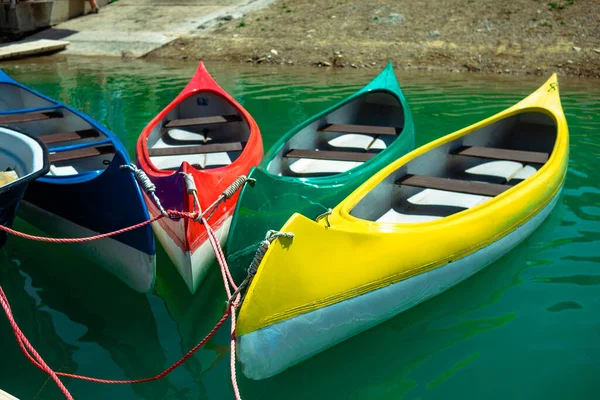 Four kayaks on the shore close-up. Multi-colored kayaks are attached to the pier.