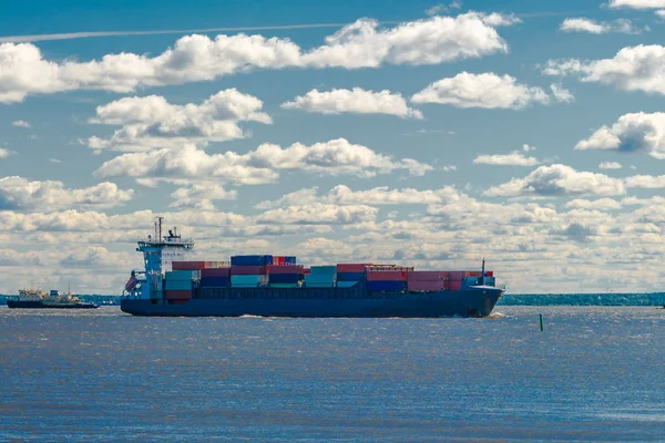 A barge floating along the sea along the shore. The sea barge is transporting goods of the appropriate destination. The sea is calm. The weather is sunny.