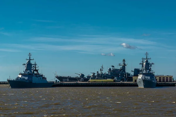 Naval base. Military ships with weapons are at the pier. Sunny day. Calm sea.