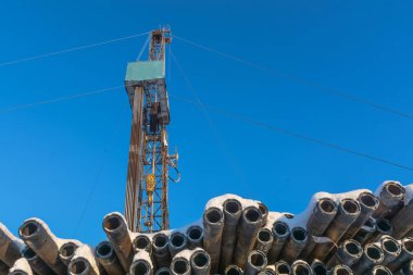 Petrol ve gaz sondaj sondaj platformu. Arka planda mavi gökyüzüdür. Borular ön planda karla kaplı. Arktik bölgede kış.
