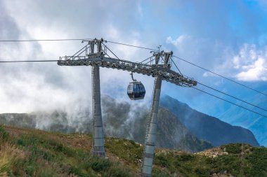 Dağlarda aşırı kablo araba sürmek. Dağlar yeşil eteklerinde. Yaz dinlenme.