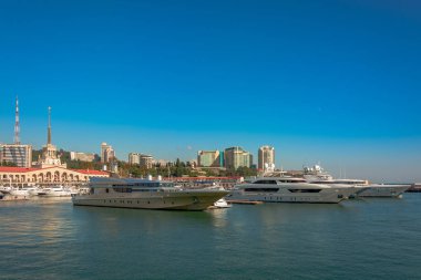 Yaz aylarında liman. Birçok farklı yat ve tekne yat limanında hazır. Yatçılar ve yolcuları denizde yelken açmaya hazırlanıyorlar. Sahil şehir bina arka planda.