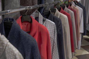 Çok renkli elbise askıları üst üste asılı. Farklı stilleri kat soyunma odası veya vitrin içinde saklanır. Arka plan renk kompozisyonu bulanık bir bakış açısı ile.