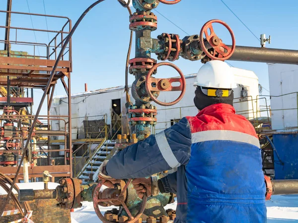 石油会社の従業員は よく仕事を実行します 噴水継手にステアリング ホイールを回転します 石油生産の背景装置 極の油田で冬の日 — ストック写真