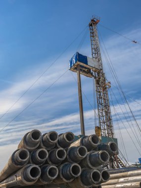 Borular ön planda matkap. Arka planda bir mobil petrol ve gaz kuyuları delme için sondaj olduğunu. Arka plan - mavi gökyüzü bulutlu.