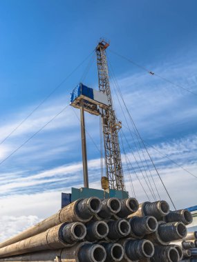 Borular ön planda matkap. Arka planda bir mobil petrol ve gaz kuyuları delme için sondaj olduğunu. Arka plan - mavi gökyüzü bulutlu.