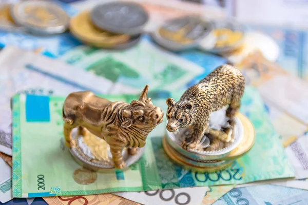 Bronze figures of a bull and a bear on the background of paper money and metal coins. Blur background and perspective. Concept and symbol of stock exchange and stock trading.