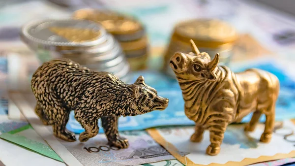 Bronz boğa ve ayı figürleri kağıt para ve metal sikke ile düzenlenmiştir. Arka plan bulanıklık. Borsa üzerinde ticaret sembolü ve kavramı.