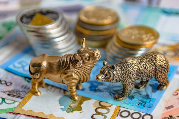 Бронзовые фигурки быков и медведей расставлены на бумажные деньги и металлические монеты. Фон размыт. Символ и концепция торгов на бирже
.