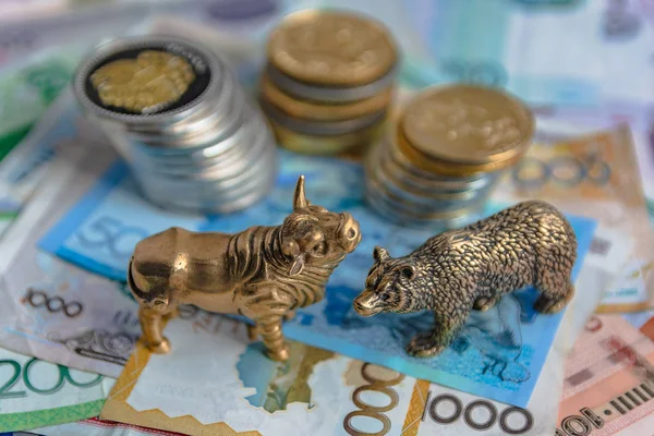 The bronze bull and bear figurines are arranged with paper money and metal coins. Blur background. Symbol and concept of trading on the stock exchange.