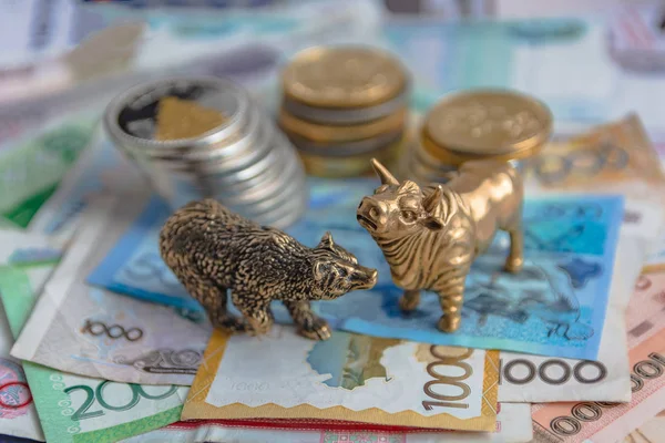 The bronze bull and bear figurines are arranged with paper money and metal coins. Blur background. Symbol and concept of trading on the stock exchange.