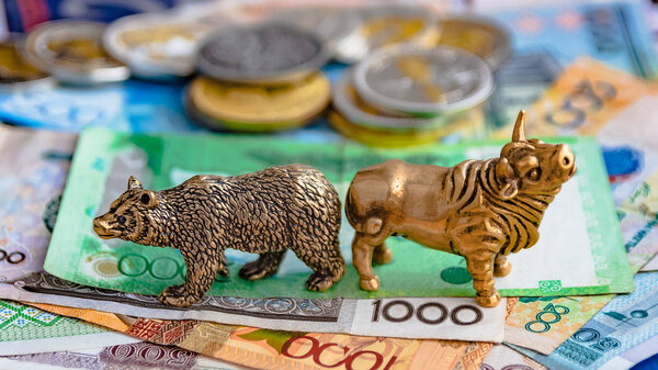 Бронзовые фигуры быка и медведя на фоне бумажных денег и металлических монет. Размытый фон и перспектива. Концепция и символ биржевой и биржевой торговли
.