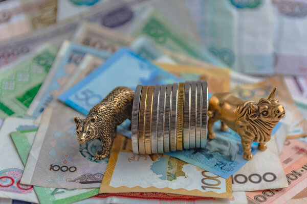 Бронзовые фигуры быка и медведя возле металлических монет на фоне бумажных денег. Размытый фон и перспектива. Концепция и символ биржевой и биржевой торговли
.