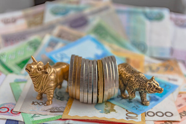 Бронзовые фигуры быка и медведя возле металлических монет на фоне бумажных денег. Размытый фон и перспектива. Концепция и символ биржевой и биржевой торговли
.