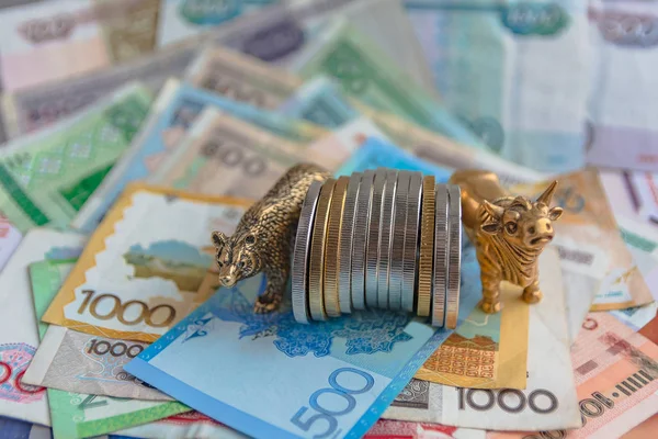 Bronze figures of a bull and a bear near metal coins on the background of paper money. Blur background and perspective. Concept and symbol of stock exchange and stock trading.
