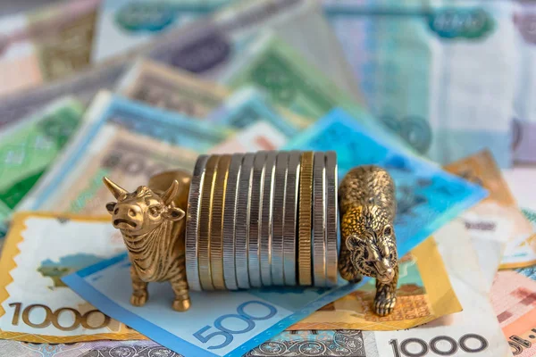 Bronze figures of a bull and a bear near metal coins on the background of paper money. Blur background and perspective. Concept and symbol of stock exchange and stock trading.