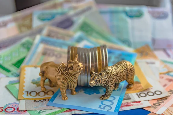 Bronze figures of a bull and a bear near metal coins on the background of paper money. Blur background and perspective. Concept and symbol of stock exchange and stock trading.