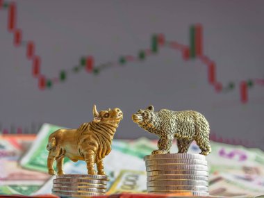 Kağıt para ve grafiklerin arka planına karşı metal sikkelerin yanında bir boğa ve bir ayının bronz figürleri. Bulanıklık arka plan ve perspektif. Borsa ve borsa işlemlerinin kavramı ve sembolü.