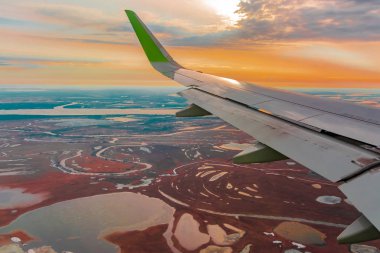 Uçak porthole bahar kuzey tundra ve göller renkli üst görünümü. Ayrıca uçan uçağın kanadı da görülebilir.
