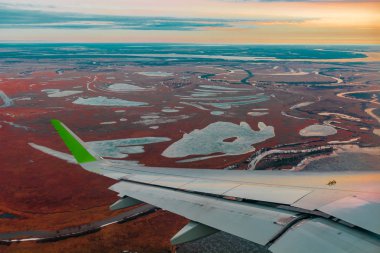 Uçak porthole bahar kuzey tundra ve göller renkli üst görünümü. Ayrıca uçan uçağın kanadı da görülebilir.