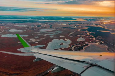 Uçak porthole bahar kuzey tundra ve göller renkli üst görünümü. Ayrıca uçan uçağın kanadı da görülebilir.