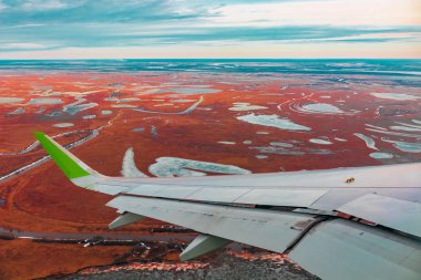 Uçak porthole bahar kuzey tundra ve göller renkli üst görünümü. Ayrıca uçan uçağın kanadı da görülebilir.