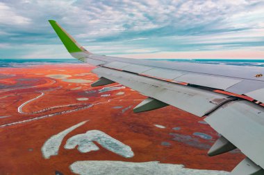 Uçak porthole bahar kuzey tundra ve göller renkli üst görünümü. Ayrıca uçan uçağın kanadı da görülebilir.