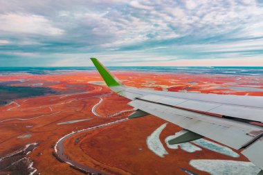 Uçak porthole bahar kuzey tundra ve göller renkli üst görünümü. Ayrıca uçan uçağın kanadı da görülebilir.