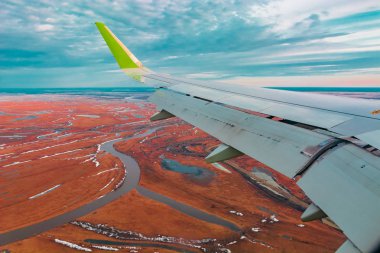 Uçak porthole bahar kuzey tundra ve göller renkli üst görünümü. Ayrıca uçan uçağın kanadı da görülebilir.