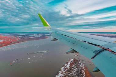 Uçak porthole bahar kuzey tundra ve göller renkli üst görünümü. Ayrıca uçan uçağın kanadı da görülebilir.