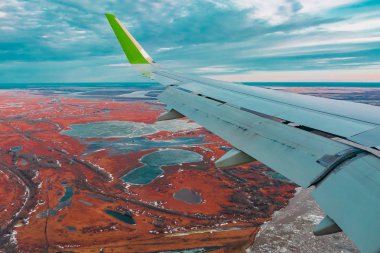 Uçak porthole bahar kuzey tundra ve göller renkli üst görünümü. Ayrıca uçan uçağın kanadı da görülebilir.
