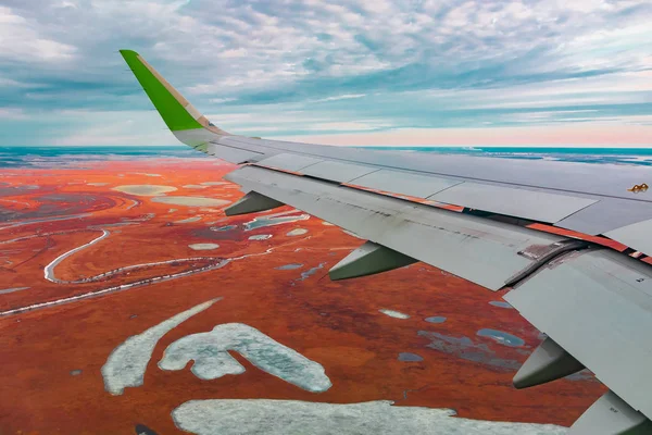 Uçak porthole bahar kuzey tundra ve göller renkli üst görünümü. Ayrıca uçan uçağın kanadı da görülebilir.