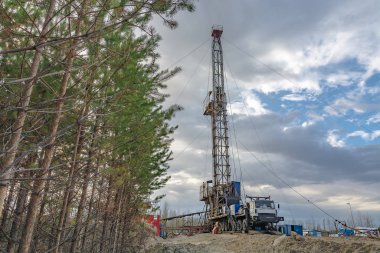 Bir petrol ve gaz alanında derin bir iyi Mobil sondaj teçhizat delme. Alan, Taiga 'daki uzak kuzey 'de yer almaktadır. Arka planda güzel dramatik günbatımı gökyüzü.