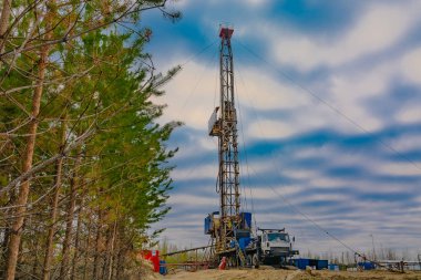 Bir petrol ve gaz alanında derin bir iyi Mobil sondaj teçhizat delme. Alan, Taiga 'daki uzak kuzey 'de yer almaktadır. Arka planda güzel dramatik günbatımı gökyüzü.