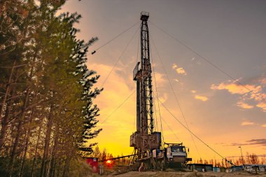 Bir petrol ve gaz alanında derin bir iyi Mobil sondaj teçhizat delme. Alan, Taiga 'daki uzak kuzey 'de yer almaktadır. Arka planda güzel dramatik günbatımı gökyüzü.