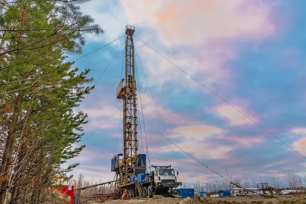 Drilling a deep well mobile drilling rig in an oil and gas field. The field is located in the Far North in the taiga. Beautiful dramatic sunset sky in the background.