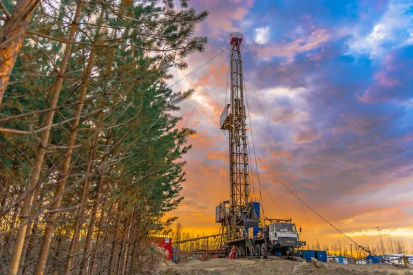 Drilling a deep well mobile drilling rig in an oil and gas field. The field is located in the Far North in the taiga. Beautiful dramatic sunset sky in the background.