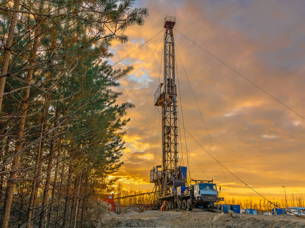 Drilling a deep well mobile drilling rig in an oil and gas field. The field is located in the Far North in the taiga. Beautiful dramatic sunset sky in the background.