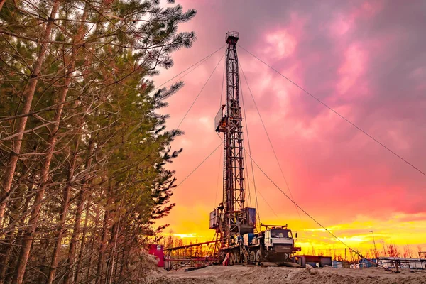 Drilling a deep well mobile drilling rig in an oil and gas field. The field is located in the Far North in the taiga. Beautiful dramatic sunset sky in the background.