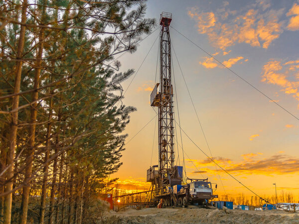 Drilling a deep well mobile drilling rig in an oil and gas field. The field is located in the Far North in the taiga. Beautiful dramatic sunset sky in the background.