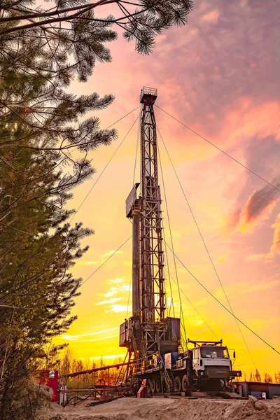 Drilling a deep well mobile drilling rig in an oil and gas field. The field is located in the Far North in the taiga. Beautiful dramatic sunset sky in the background.