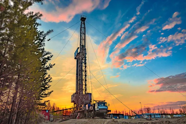 Drilling a deep well mobile drilling rig in an oil and gas field. The field is located in the Far North in the taiga. Beautiful dramatic sunset sky in the background.