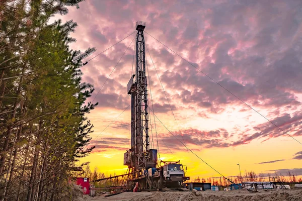 Drilling a deep well mobile drilling rig in an oil and gas field. The field is located in the Far North in the taiga. Beautiful dramatic sunset sky in the background.